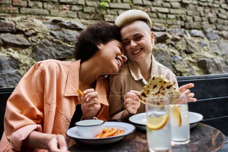 Two diverse women enjoy a meal together at a cafe.