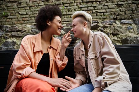 Una pareja diversa de lesbianas con estilo comparten un momento de cercanía en un acogedor café.