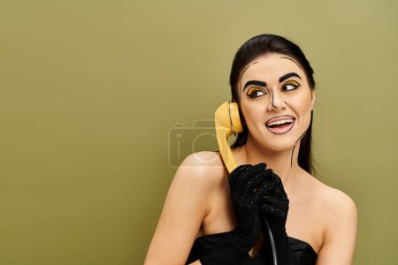 Woman in black dress with yellow phone to ear, showcasing pop art makeup and black gloves.