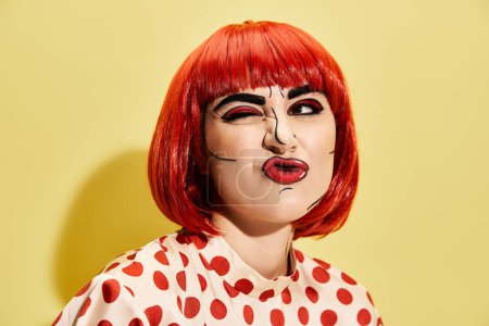 A close-up of a pretty redhead person with creative pop art makeup, wearing a polka dot blouse on a yellow background.