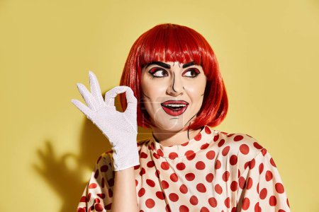 A striking redhead woman with pop art makeup wears a polka dot shirt and white gloves on a yellow background.