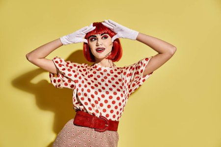 A pretty redhead woman in a polka dot top and white gloves with creative pop art makeup on a yellow background.