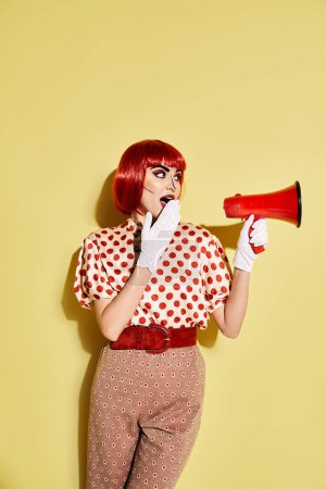 Una pelirroja feroz sostiene un megáfono rojo y blanco, exudando confianza con su maquillaje pop art y su blusa de lunares.