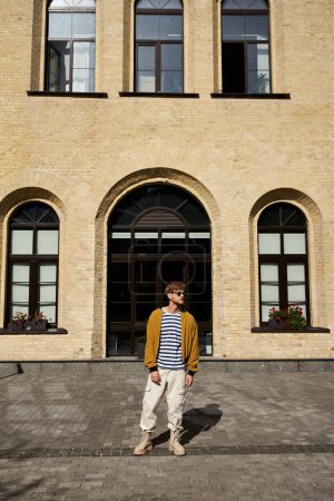 Junger rothaariger Mann in Debonair-Kleidung steht in Ehrfurcht vor einem majestätischen großen Gebäude.