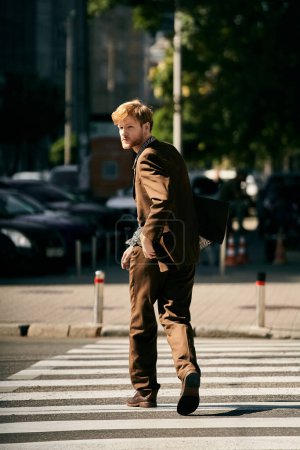 A debonair young man with red hair crossing a city crosswalk.