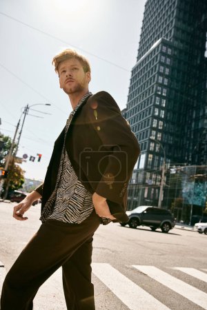 Young red-haired man in stylish suit confidently crossing a bustling city street.