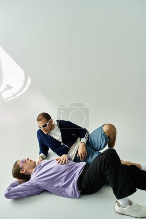 Ein Mann liegt auf dem Boden, während der andere neben ihm sitzt und in Gespräche vertieft ist..