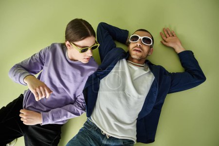 Photo for Two men enjoying a relaxing moment laying on the ground wearing sunglasses. - Royalty Free Image