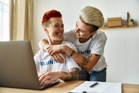 Un homme et une femme s'embrassent en regardant un ordinateur portable, s'engagent dans un travail bénévole avec empathie et unité.