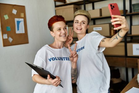 Téléchargez les photos : Deux jeunes femmes en t-shirts bénévoles se tiennent côte à côte, incarnant le travail d'équipe et la collaboration dans le travail de charité. - en image libre de droit