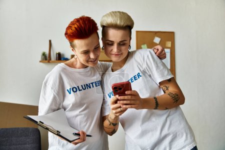 A lesbian couple, clad in volunteer t-shirts, joined together in charity work.