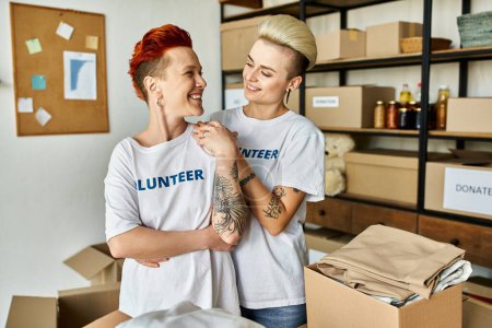 Una pareja de lesbianas con camisetas voluntarias trabajan juntas en caridad.