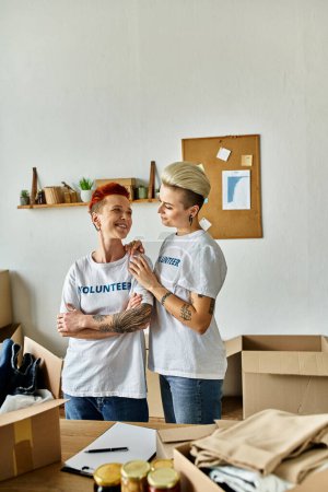 Téléchargez les photos : Two women in volunteer t-shirts, partners in charity work, standing side by side. - en image libre de droit
