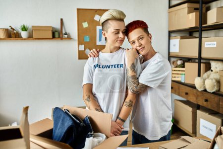 Ein junges lesbisches Paar in freiwilligen T-Shirts beim Auspacken von Kartons, vereint in wohltätiger Arbeit.