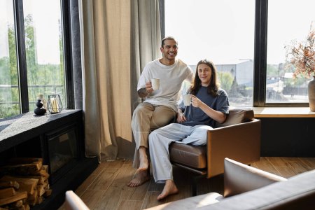 Ein junges schwules Paar entspannt sich in einem modernen Haus, genießt Kaffee und Gesellschaft der anderen.