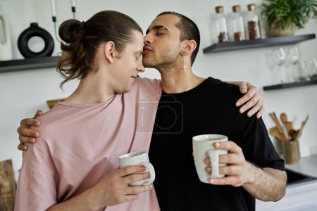 A young gay couple enjoys a cozy moment together in their modern home, sharing coffee and a tender kiss.