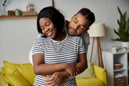 An African American couple embraces in their home, full of love and happiness.