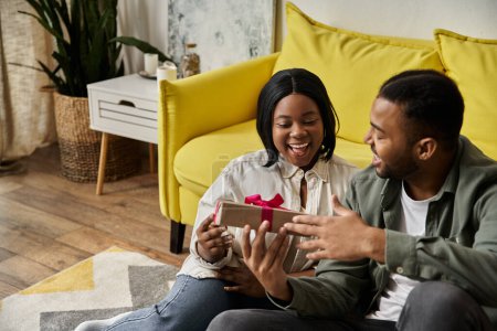 Ein glückliches afroamerikanisches Paar tauscht zu Hause ein Geschenk.