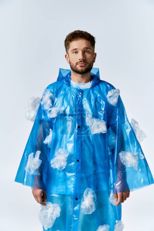 A man stands in a blue plastic raincoat decorated with plastic bags.