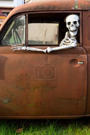 Téléchargez les photos : Squelette humain assis dans une vieille voiture rouillée et regardant par la fenêtre - en image libre de droit