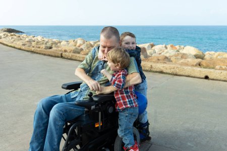 Behinderter fährt mit kleinen Jungen Inlineskaten am Meer