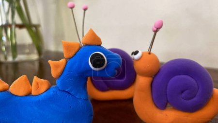Title Purple and orange clay snails with eyes and antennae. Suitable for childrens book illustrations, educational materials, and naturethemed designs.