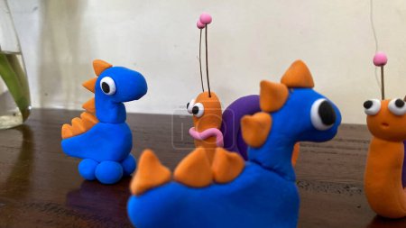 Three colorful dinosaurs on a table. Suitable for kids products, educational materials, dinosaurthemed designs, and playful illustrations.