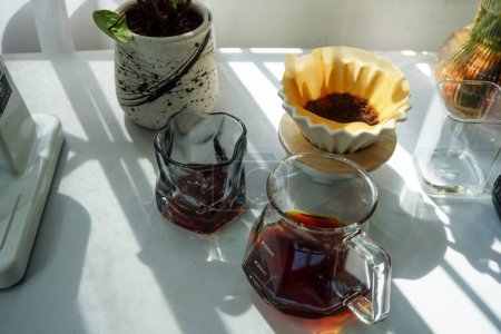 es gibt drei Gläser Kaffee und einen Serverkaffee mit Origami-Tropfer auf einem Tisch, perfekt für Speisen- und Getränkekonzepte, Einladungen zu Party-Veranstaltungen.
