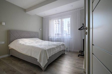 Foto de Puerta abierta a un pequeño dormitorio blanco brillante con cama doble grande - Imagen libre de derechos
