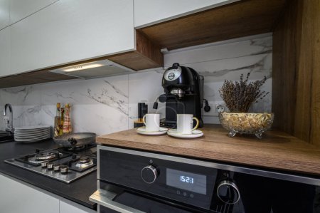 Téléchargez les photos : Détails de la cuisine moderne de luxe blanche et noire, plan de travail avec four, cafetière et autres appareils - en image libre de droit
