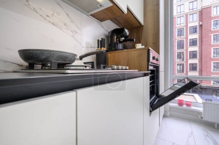 Foto de Amplio interior de cocina moderna de lujo en blanco y negro, vista de primer plano al mostrador de la cocina y a la puerta del horno abierto - Imagen libre de derechos