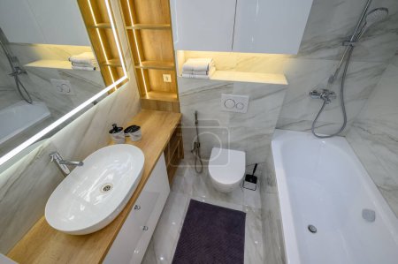 Téléchargez les photos : Salle de bain de luxe intérieure avec un bol de toilette, carreaux de marbre sur les murs et un grand miroir, vue à angle bas - en image libre de droit