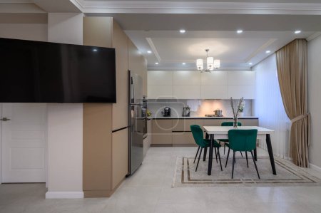 Téléchargez les photos : Cuisine moderne de luxe beige et blanche avec salle à manger à l'intérieur d'un studio - en image libre de droit
