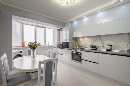 Foto de Interior of white trendy modern kitchen with dining table - Imagen libre de derechos