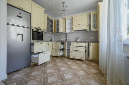 Téléchargez les photos : Real showcase interior of modern trendy cream colored kitchen, drawers retracted - en image libre de droit