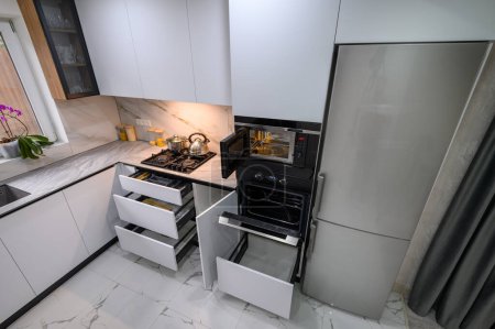 Eine geräumige und modernisierte Küche mit einem weißen Farbschema, mit ausziehbaren Regalen für bequeme Lagerung und Organisation, hohe Blickwinkel