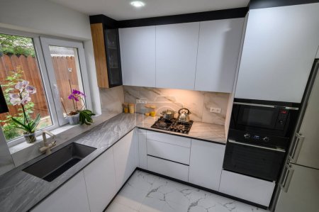 Eine geräumige und modernisierte Küche mit Schwarz-Weiß-Farbschema, mit ausziehbaren Regalen für bequeme Lagerung und Organisation, hohe Blickwinkel