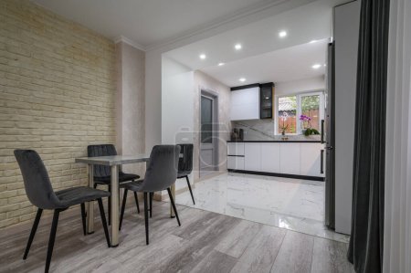 Nuevo gran cocina blanca moderna y bien diseñada y comedor interior después de la renovación en el apartamento estudio