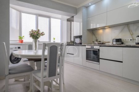 Téléchargez les photos : Intérieur de la cuisine moderne à la mode blanche avec table à manger - en image libre de droit