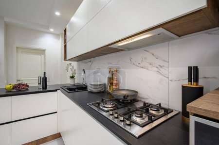 Foto de Detalles de cocina moderna de lujo blanco y negro, primer plano de la encimera con estufa de gas y otros electrodomésticos - Imagen libre de derechos