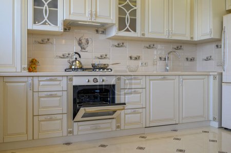 Photo for Classic white and beige kitchen furniture with oven open in studio apartment - Royalty Free Image