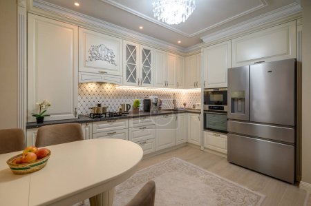 Foto de Hermosa cocina de color beige con una gran mesa de comedor y electrodomésticos de última generación - Imagen libre de derechos