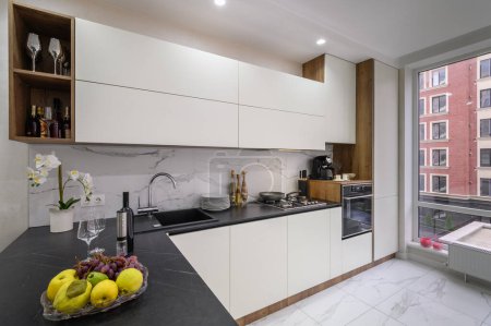Interior moderno de la cocina de lujo en blanco y negro, primer plano de la encimera con frutas y vino en primer plano