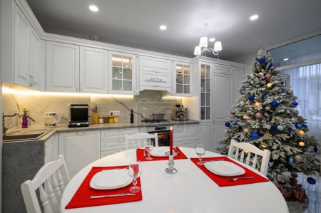 Photo for Interior of bright modern kitchen with dining table decorated with Christmas tree - Royalty Free Image