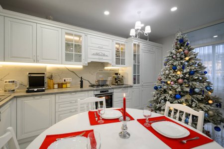 Foto de Interior de la cocina moderna y luminosa con mesa de comedor decorada con árbol de Navidad - Imagen libre de derechos