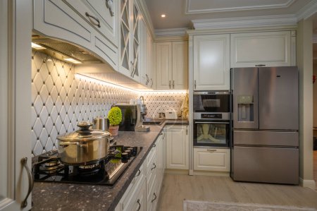 Foto de Elegante cocina de concepto abierto con un esquema de color beige y elementos de diseño clásico, primer plano de la encimera - Imagen libre de derechos