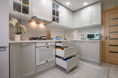 Foto de Primer plano de blanco y gris nuevo interior de la cocina moderna bien diseñada, algunos cajones sacados - Imagen libre de derechos