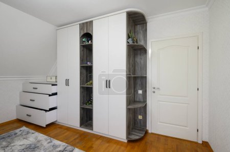 Foto de Gran armario blanco y aparador en la sala de estar con suelo de madera, algunos cajones retraídos - Imagen libre de derechos