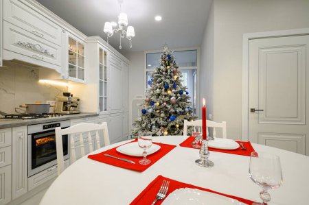 Foto de Interior de la cocina moderna y luminosa con mesa de comedor decorada con árbol de Navidad - Imagen libre de derechos