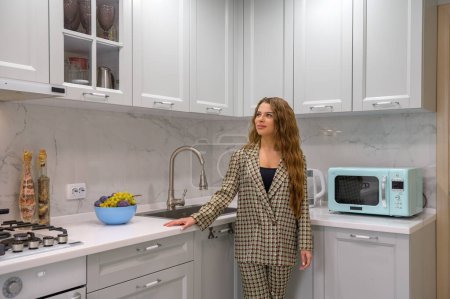 Téléchargez les photos : Portrait de jeune femme au foyer mignonne dans l'intérieur de la cuisine à l'arrière-plan - en image libre de droit